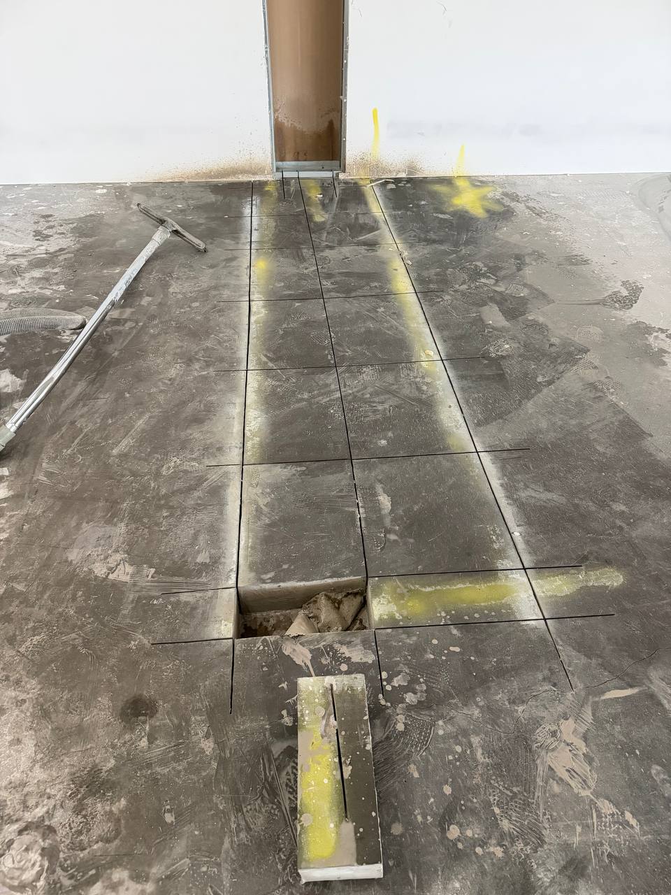 Precision slab cutting with yellow guide marks for plumbing trench access in basement