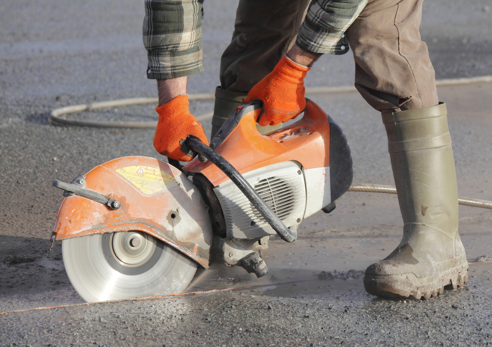 Handheld diamond cutoff saw cutting concrete road surface for emergency repair