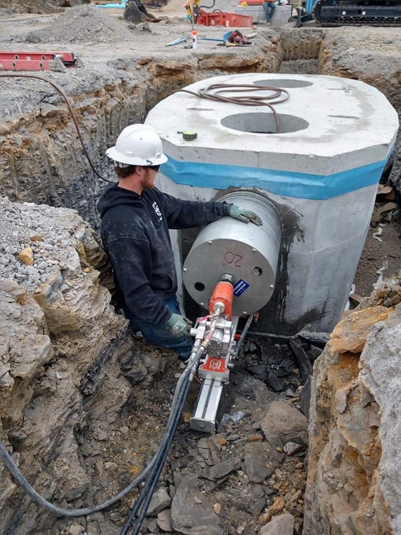 Large-diameter core drilling into concrete manhole structure on excavation site