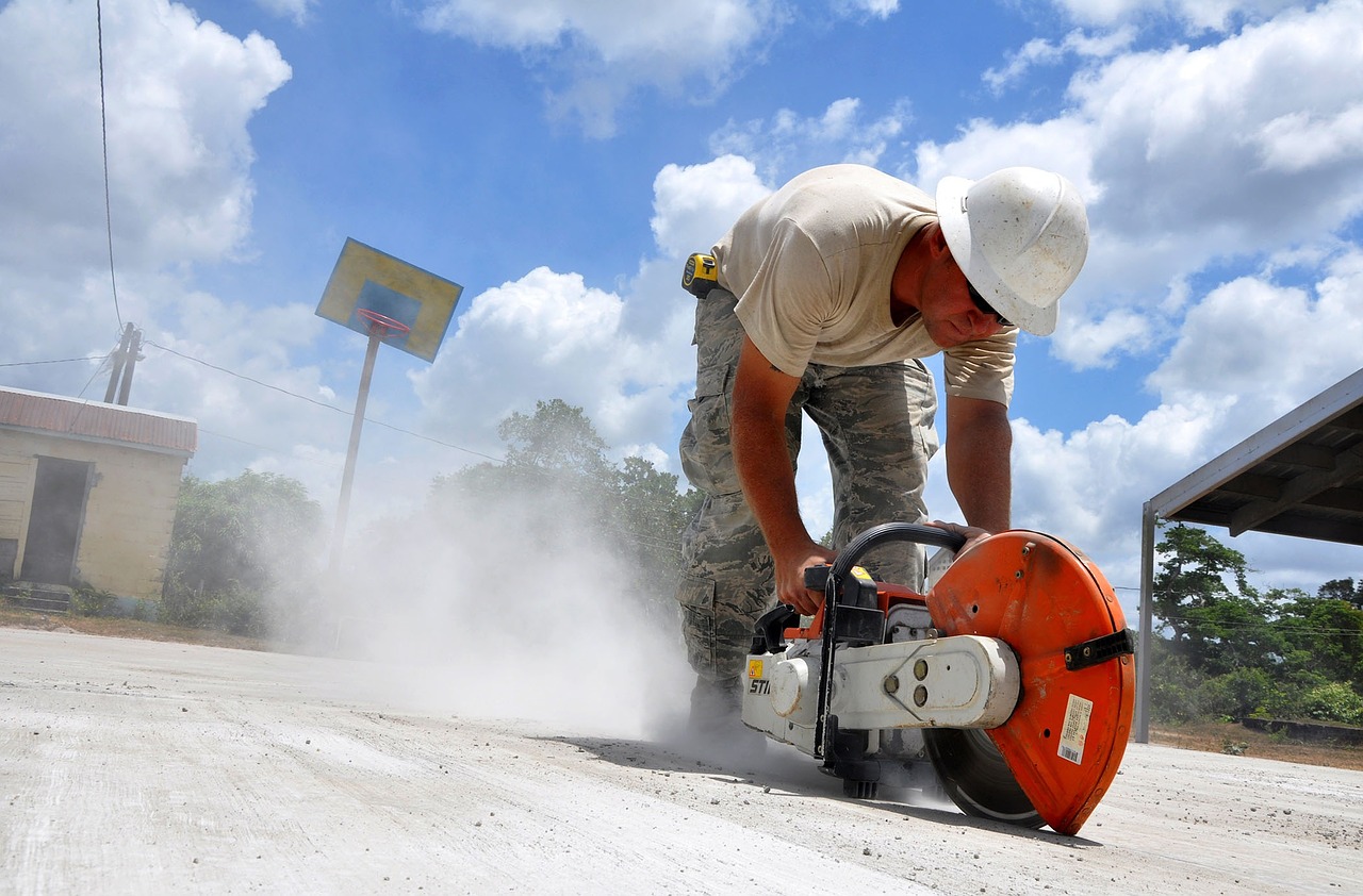 Construction worker using Stihl handheld concrete cutoff saw on outdoor slab